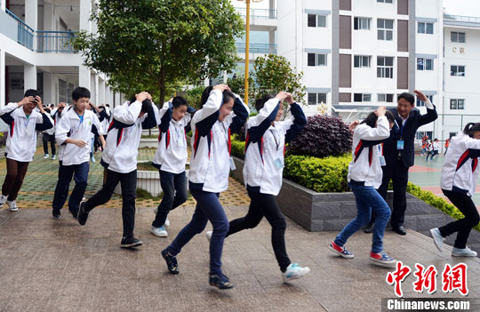 资料图：4月22日，广西龙胜各族自治县初级中学开展了突发事件安全应急疏散演练。图为学生们用双手护住头部快速向学校安全场所撤离。中新社发 石农兵 摄